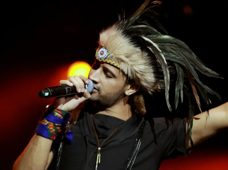Atif Aslam singing on stage in a feathered headdress