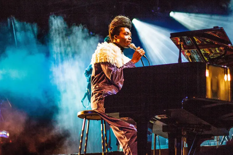 Benjamin Clementine playing piano on a smoke-filled stage
