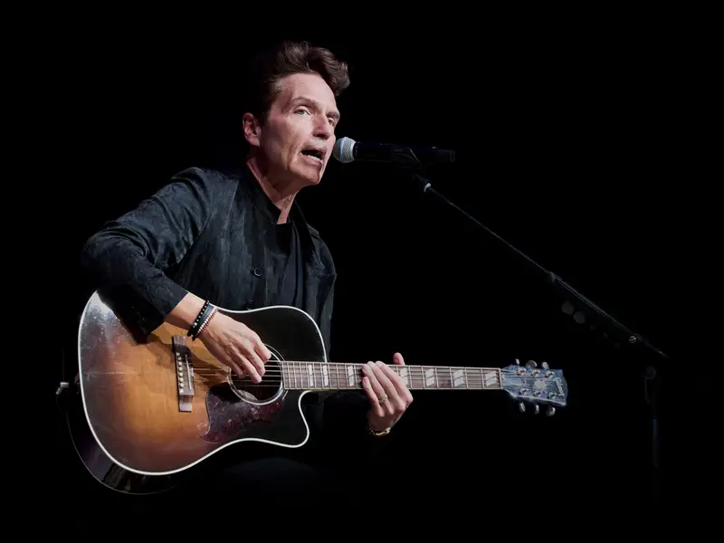 Richard Marx playing an acoustic guitar on stage