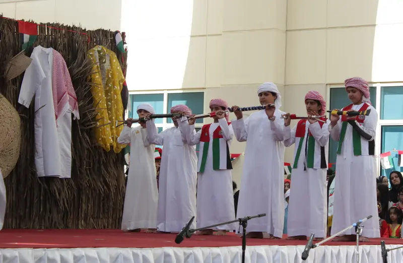 Emirati boys performing a traditional Yowla dance on stage