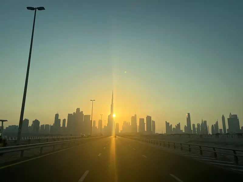 The Dubai skyline with Burj Khalifa silhouetted against a low sun