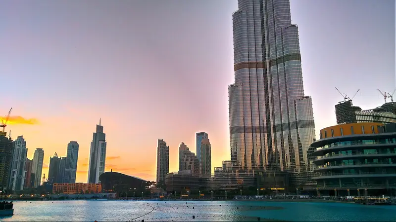Burj Khalifa rising above the Dubai Fountain lake at dusk